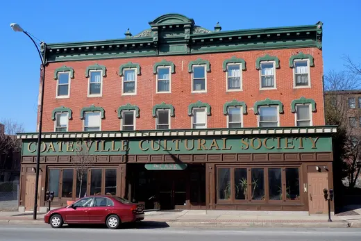 Three-story brick building labeled 'Coatesville Cultural Society' on a street., Coatesville, Pennsylvania
