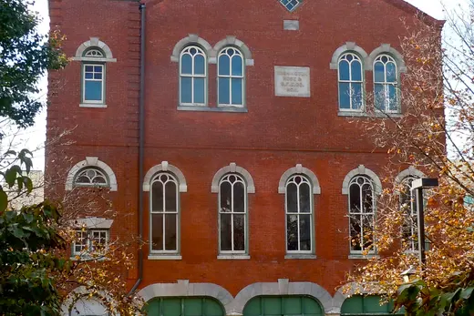 Brick firehouse building with green garage doors and parked cars., Conshohocken, Pennsylvania