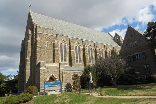 Stone church building and grounds with a statue and sign, Darby, Pennsylvania