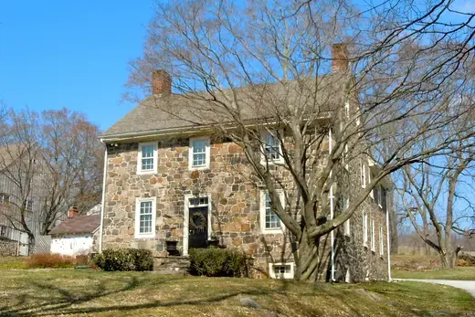 Stone two-story house with leafless trees on a sunny day, East Bradford Township, Pennsylvania