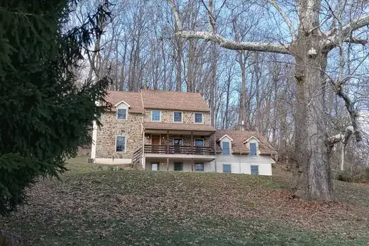 Stone house on a grassy hill with leafless trees behind, East Nantmeal Township, Pennsylvania