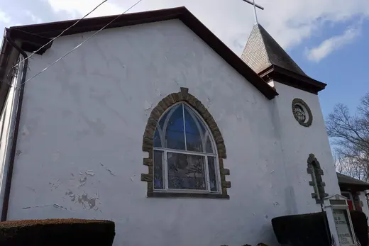 White church exterior with arched stained-glass window and steeple., East Nantmeal Township, Pennsylvania