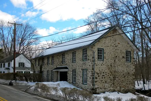 Stone building and house beside a snowy roadside under blue sky., Easttown Township, Pennsylvania