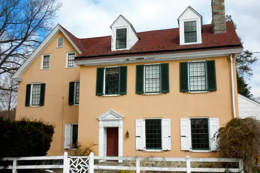 Two-story peach house with green shutters and white picket fence., Easttown Township, Pennsylvania