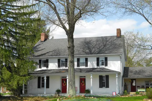 Two-story white house with red doors and large tree in front., Franklin Township, Pennsylvania