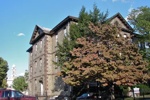 Stone building with trees and parked cars on a sunny street., Germantown, Pennsylvania
