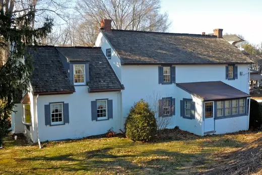 White two-story house with blue shutters and a brown roof in yard, Limerick Township, Pennsylvania