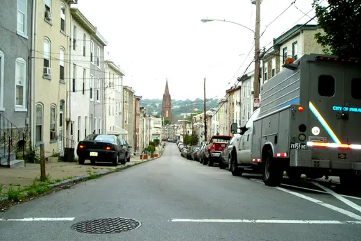Residential city street with parked cars and distant church steeple, Manayunk, Pennsylvania