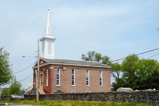 Brick church with white steeple behind a stone wall on a suburban street, Marcus Hook, Pennsylvania