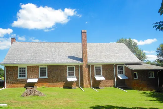 Brick house with chimney and green lawn under blue sky, New Garden Township, Pennsylvania