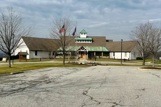Large civic building with green metal roof, flags, parking lot in front, New Garden Township, Pennsylvania