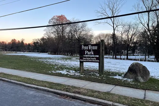 Park entrance sign reading 'Penn Wynne Park' beside a sidewalk and snow., Penn Wynne, Pennsylvania