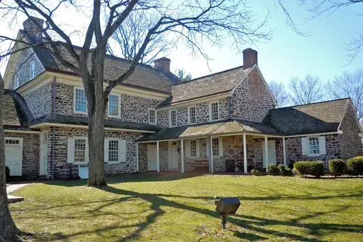 Stone colonial house with porch and bare trees on lawn, Pottsgrove, Pennsylvania