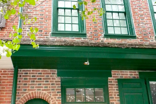 Brick facade with green-trimmed windows and door numbered 702, Queen Village, Pennsylvania