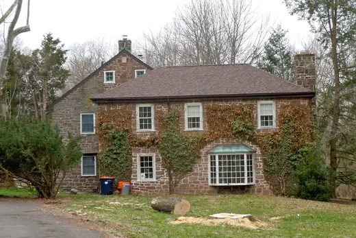 Stone two-story house with ivy and bay window in a wooded yard., Skippack Township, Pennsylvania