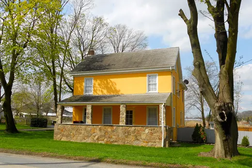 Yellow two-story house with stone porch and large trees., Toughkenamon, Pennsylvania