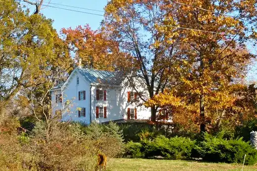 White house among autumn trees beside a rural road., Upper Gwynedd Township, Pennsylvania