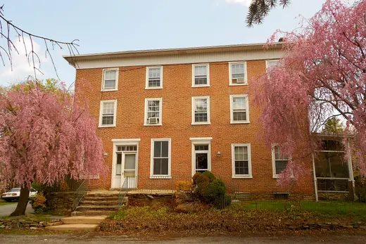 Three-story brick building flanked by pink flowering trees, West Marlborough Township, Pennsylvania