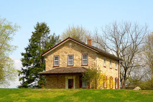 Stone farmhouse on grassy hill with trees and clear blue sky., West Marlborough Township, Pennsylvania