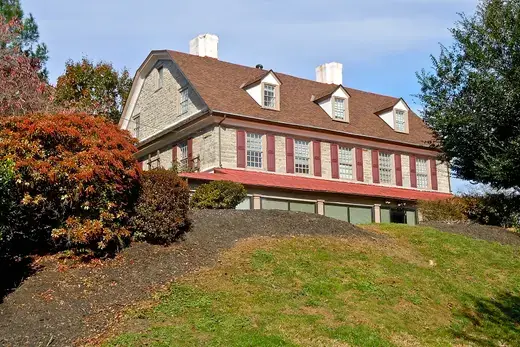 Stone house with red shutters and dormers on a grassy hillside., Whitemarsh Township, Pennsylvania