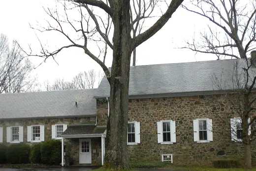 Stone building with white shutters and large trees in front., Willistown Township, Pennsylvania